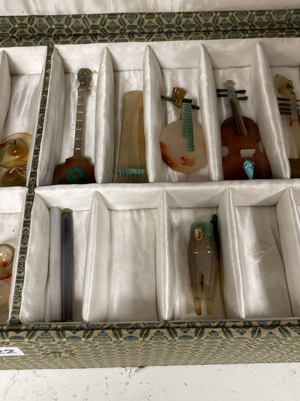 A collection of Chinese carved agate and other hardstone models of miniature musical instruments, together with hardwood stands, boxed